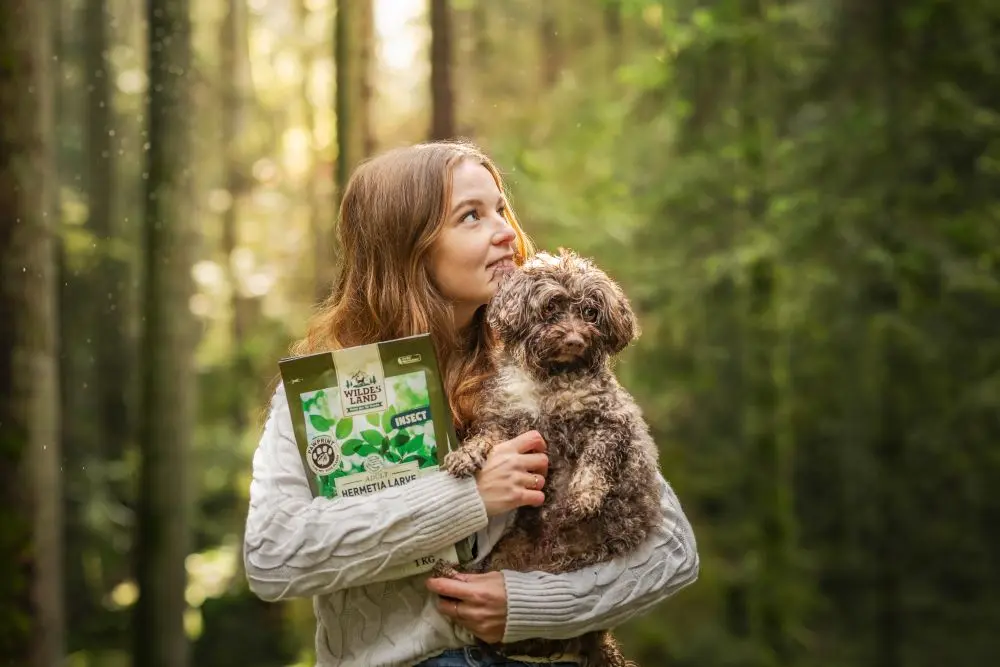 Mädchen hat einen kleinen Hund auf dem Arm und eine 1kg Packung PawPrint Insect