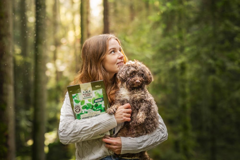 Mädchen hat einen kleinen Hund auf dem Arm und eine 1kg Packung PawPrint Insect
