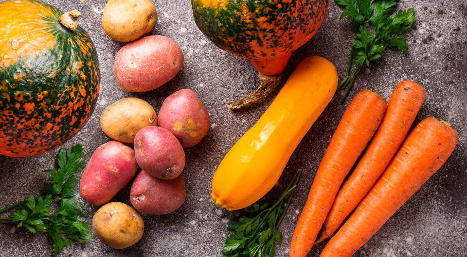 Auf einem Tisch liegen Kürbisse, Kartoffeln, Karotten und Zucchini